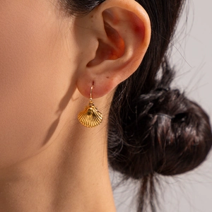 Macro shot of gold seashell drop earrings showing delicate metal texture and ocean style
