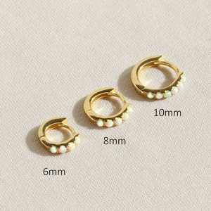 Detailed comparison of 6mm, 8mm, and 10mm gold opal huggie earrings on textured fabric