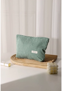 Close-up of green corduroy makeup bag with H & R BAG label on a wooden tray