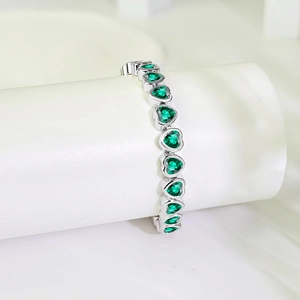 Macro detail of heart-cut green zircon stones on a silver-plated tennis bracelet