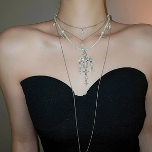 Close-up of layered silver cross necklace with white pearls and sparkling rhinestones