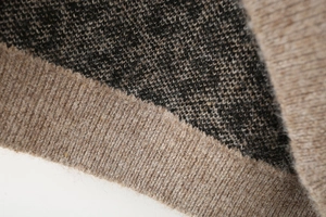 Détail de la texture en maille jacquard léopard beige et gris avec poignets côtelés