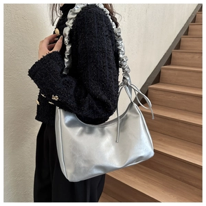 Detail of silver metallic shoulder bag with ruffled strap and drawstring accents