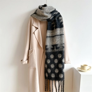 Detail of black and grey polka dot scarf with fringes on a beige wool coat
