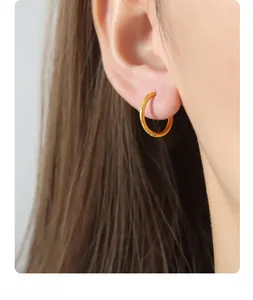 Close-up of minimalist gold plated double circle earrings worn by a model in soft light