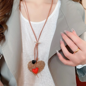 Detailed view of acrylic heart pendants on leather cord necklace worn with outfit