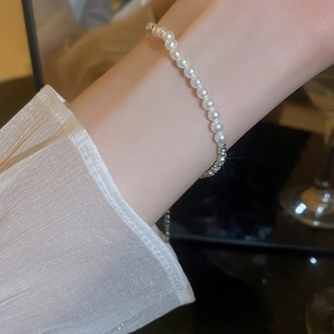 Detail showing elegant white pearl and silver chain bracelet worn on a woman's wrist