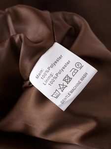 Nahaufnahme des Pflegeetiketts mit 100% Polyester Material und den Waschhinweisen