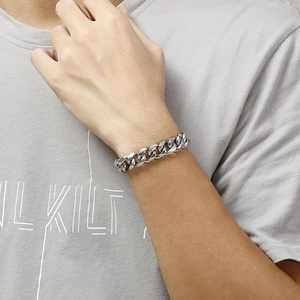 Close-up of a wide polished stainless steel Cuban link bracelet worn on a wrist