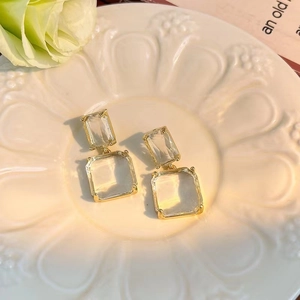 Elegant geometric square gold drop earrings with transparent glass on a vintage background