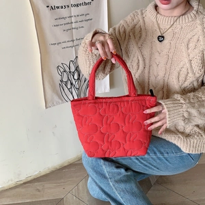 Close-up detail of soft quilted red tote bag featuring cute bunny pattern embroidery