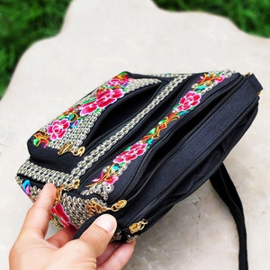 Detail of floral embroidery and gold metal zippers on ethnic canvas crossbody bag
