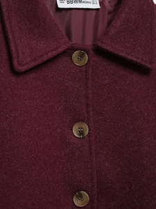 Detail of red wool jacket collar with tortoiseshell buttons and textured fabric finish