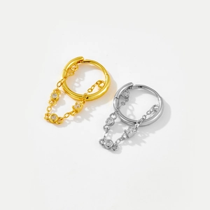 Detail of silver and gold hoop earrings with chain pendants and zircon stones