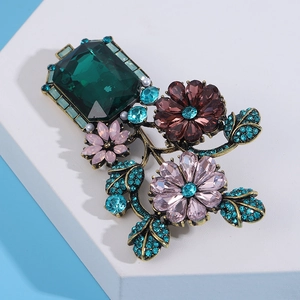 Detail of baroque vase brooch with emerald crystals and rhinestones on blue background