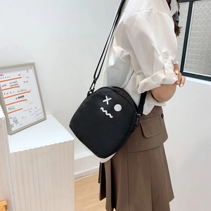 Détail du sac à bandoulière en toile noire avec visage de dessin animé sur mannequin
