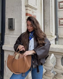 Close-up of premium brown leather handbag texture and vintage oversized faux leather jacket