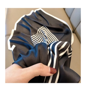 Detail shot of black silk scarf with white stripes showing soft texture and elegant drape