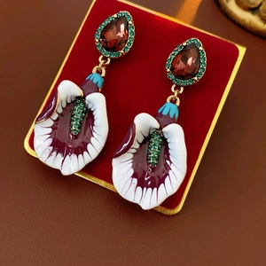 Vintage calla lily earrings with purple enamel, red gems and green crystals on red velvet