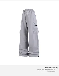 Detalle de pantalones cargo gris claro con cintura elástica y bolsillos con cremallera