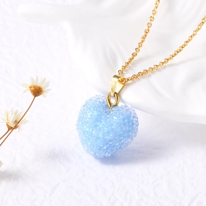 Détail du collier avec pendentif cœur bleu clair et texture cristalline scintillante