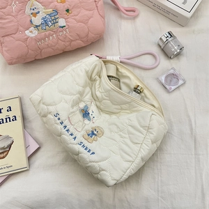 Detail of quilted heart pattern and cute animal embroidery on a pink vanity bag