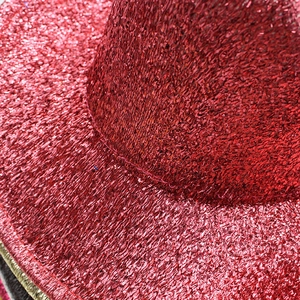 Close-up of shiny red metallic thread texture and fine stitching on the cowboy hat