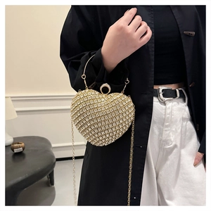 Detail of a sparkling rhinestone heart evening bag with silver chain worn by a model
