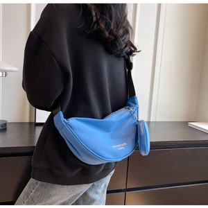 Borsa a mezzaluna in nylon blu con pochette e tracolla regolabile indossata