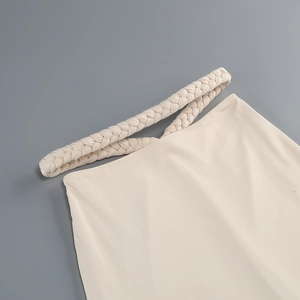 Detailed close-up of the elegant cream knitted fabric and decorative braided waist texture