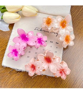 Close-up of candy-colored plumeria flower hair clips in pink and orange gradients