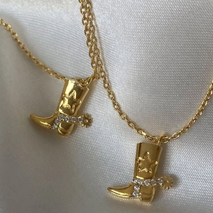 Golden cowboy boot pendant necklace with star engraving and crystals on white silk