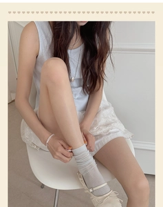 Detail of light gray ribbed mid-calf socks styled with lace skirt and ballet flats