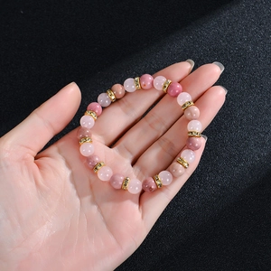 Gros plan d'un bracelet en perles de quartz fraise avec entretoises dorées