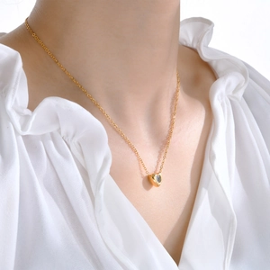 Detail of heart pendant necklace with clear zircon stone on a gold-tone delicate chain