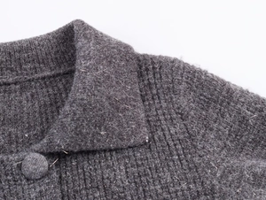 Detailed view of grey ribbed knit cardigan featuring fabric-covered button and soft texture