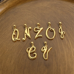 Polished 18K gold stainless steel alphabet charms on a rustic wooden display