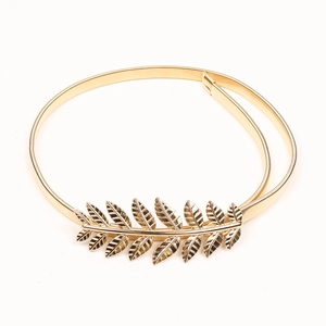 Detail of golden metal elastic belt featuring an intricate olive leaf buckle design