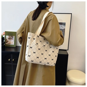 Detail of a large corduroy tote bag with black bow patterns shown on a shoulder