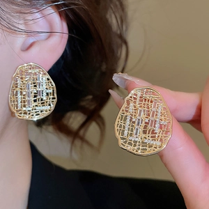 Détail macro de boucles d'oreilles ovales ajourées dorées avec cristaux de zircon brillants