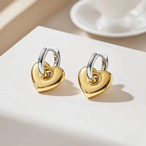Macro shot of stylish gold heart pendants on silver metal hoops on a white platform