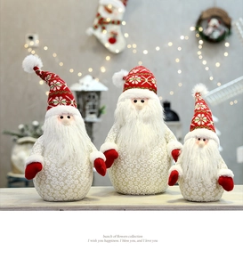 Tre peluche di Babbo Natale con trama in pizzo e cappelli a fiocco di neve su legno