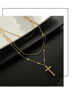 Close-up of a three-layer golden stainless steel necklace with a cross pendant design