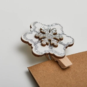 Wooden snowflake clips with silver glitter for Christmas tree decor on craft paper