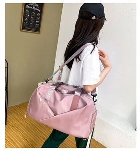 Pink fitness bag with separate wet-dry compartment carried over the shoulder by a model
