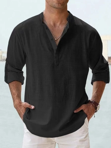 Detail of men's black linen shirt featuring a buttoned Henley collar and rolled sleeves