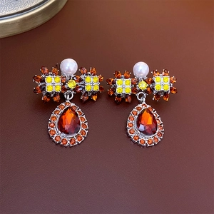 Macro shot of vintage silver earrings featuring orange rhinestones and white pearls
