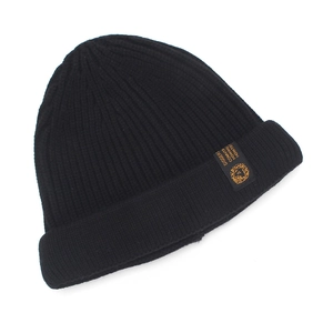 Detail of black ribbed knit beanie featuring an orange lion logo patch for men