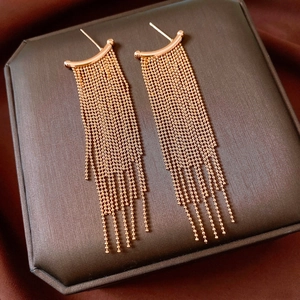 Detailed view of rose gold tassel earrings with metallic bead chains on silk