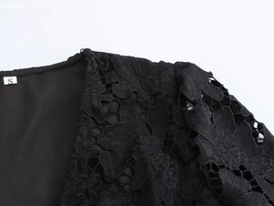 Dettaglio spalla e scollatura in pizzo nero con etichetta taglia S su sfondo bianco